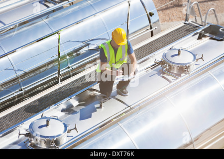 Lavoratore con tavoletta digitale sulla parte superiore di acciaio inox autocisterna per il latte Foto Stock