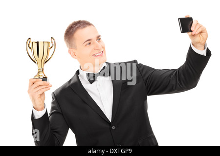Maschio elegante tenendo un trofeo e prendendo un selfie con telefono Foto Stock
