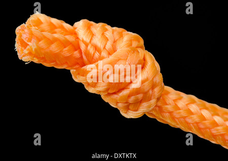 Nodo. Primo piano immagine di spessore stringa arancione legato con un nodo, con uno sfondo nero. Foto Stock