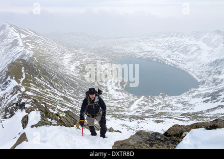 Hill Walker con ghiaccio Ax sul bordo Swrirral con Red Tarn sotto Lake District Cumbria Regno Unito Foto Stock