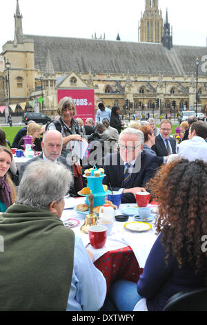 La piazza del Parlamento, Londra, Regno Unito. Il 31 marzo 2014. Norman Lamb MP (centro) il Ministro di Stato per la cura e il supporto si siede ad un tavolo gustando il tè e dolci in piazza del Parlamento a un evento in cui, "oggi (lunedì 31 marzo), uno del Regno Unito più stabilito le associazioni di beneficenza che offrono assistenza e alloggio per gli anziani, la società Abbeyfield, firmato fino ai cittadini del Regno Unito la cura sociale Carta e ha accettato di pagare il loro personale i salari.' Credit: Matteo Chattle/Alamy Live News Foto Stock