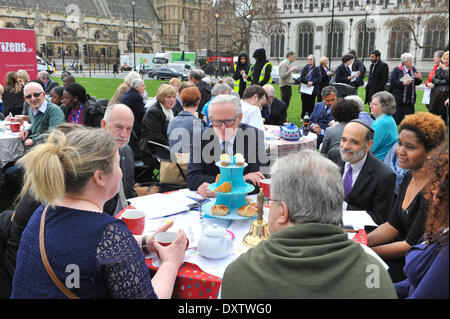 La piazza del Parlamento, Londra, Regno Unito. Il 31 marzo 2014. Norman Lamb MP (centro) il Ministro di Stato per la cura e il supporto si siede ad un tavolo gustando il tè e dolci in piazza del Parlamento a un evento in cui, "oggi (lunedì 31 marzo), uno del Regno Unito più stabilito le associazioni di beneficenza che offrono assistenza e alloggio per gli anziani, la società Abbeyfield, firmato fino ai cittadini del Regno Unito la cura sociale Carta e ha accettato di pagare il loro personale i salari.' Credit: Matteo Chattle/Alamy Live News Foto Stock