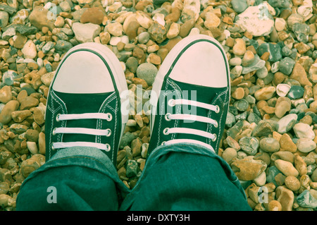 Piedi in formatori sulla spiaggia ghiaiosa Foto Stock