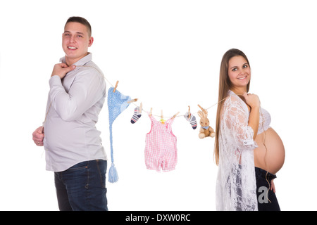 Felice coppia incinta posa con vestiti del bambino la linea Foto Stock