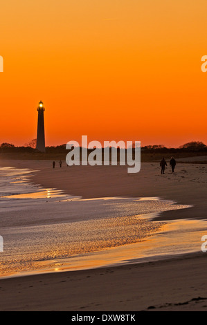 La gente camminare sulla spiaggia al tramonto a Cape May, New Jersey, Stati Uniti d'America con il Cape May Point Lighthouse in background. Foto Stock