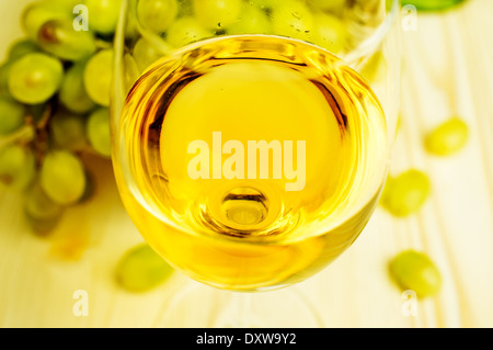 Vino bianco in un bicchiere di close-up. Background grappolo di uva Foto Stock