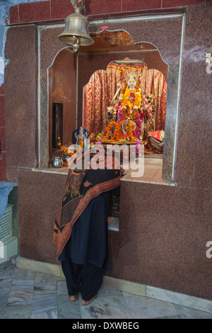 India, Dehradun. Donna orante presso il santuario della dea Maa Durga, cavalcare la tigre, armati per distruggere i demoni. Foto Stock