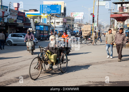 India, Dehradun. Traffico in corrispondenza di una intersezione, l'uomo in una tre ruote di mano-powered ciclo. Foto Stock