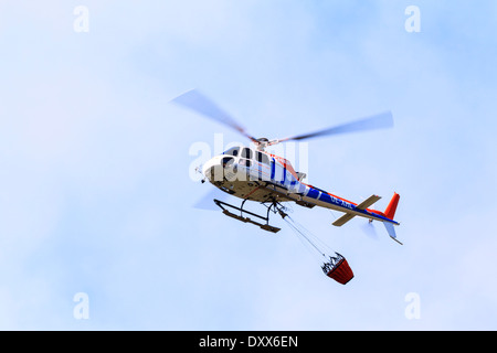 Elicottero con un secchio di acqua durante un incendio di foresta, Tirolo, Austria Foto Stock