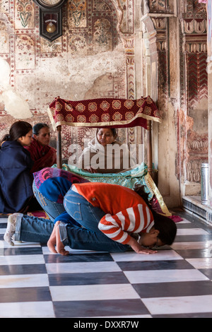 India, Dehradun. Giovani donne in jeans blu Pregare prima del santuario interiore di un tempio sikh. La donna si legge la Scrittura sacra per i visitatori. Foto Stock