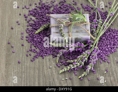 A base di erbe di sapone di lavanda e sale da bagno con fiori freschi su sfondo di legno Foto Stock