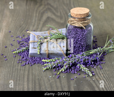 A base di erbe di sapone di lavanda e sale da bagno con fiori freschi su sfondo di legno Foto Stock