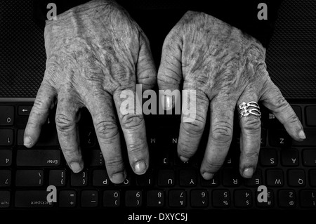 Primo piano della vecchia donna con le mani Artrite su una tastiera di computer in bianco e nero Foto Stock