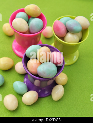 Piccole uova di Pasqua nel eggcup rosa su sfondo verde Foto Stock