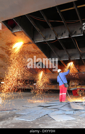 Le scintille volano come acciaio viene tagliata da un vecchio chiatta da un ossi-acetilene torcia presso un cantiere in Malaysia. Foto Stock
