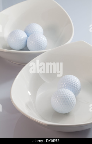 Due ceramiche bianche bocce e palline da golf Foto Stock
