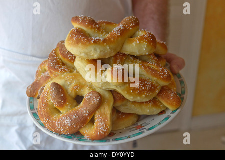 Lo chef offre una piastra riempita con appena sfornato pretzel morbidi Foto Stock