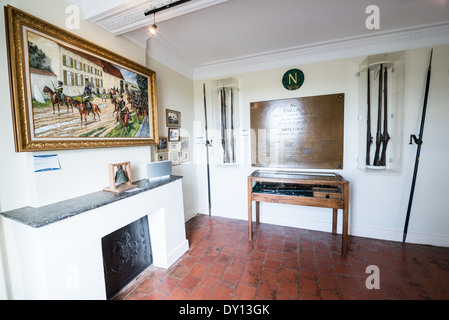 VIEUX-GENAPPE, Belgio - la sala Aides-de-Camp a Ferme du Caillou espone manufatti militari provenienti dall'ultimo quartier generale di Napoleone prima della battaglia di Waterloo. Una targa centrale di bronzo elenca lo staff imperiale che occupò questo centro di comando il 17 e 18 giugno 1815. A fianco del roster ci sono armi francesi della campagna insieme ai moschetti inglesi Brown Bess, l'arma da fuoco standard della fanteria delle forze avversarie di Wellington. Foto Stock
