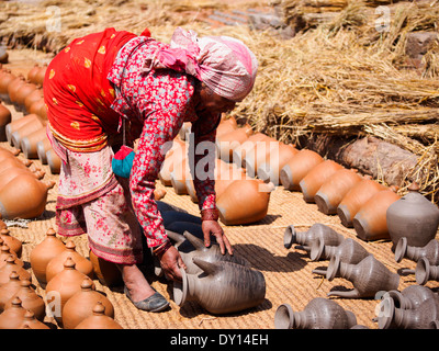 Donna di tornitura di argilla umida in ceramica come asciuga al sole nella famosa Piazza di ceramiche di Bhaktapur, Nepal Foto Stock