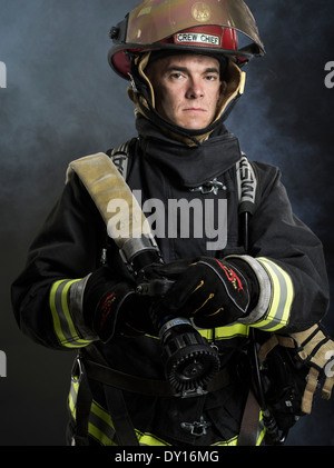 Firefighter maschio in estinzione strutturali uniforme con apparato di respirazione e ax Foto Stock