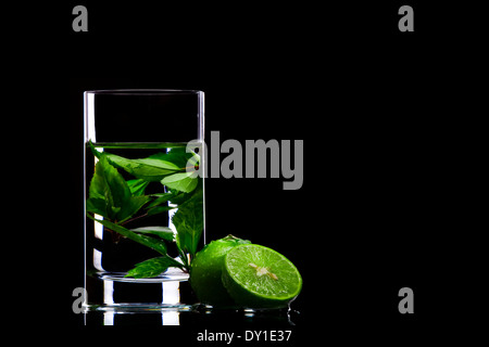 Vista di vetro riempita con il tè verde e alcuni tigli a parte Foto Stock