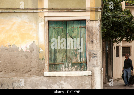 Verde nella finestra ritagliata in giallo, peeling muro di pietra Foto Stock