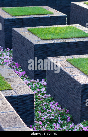 L'ardesia pietre miliari con manto erboso e Impatiens "Cupido rosa', Occupato Lizzies piantati tra. Foto Stock