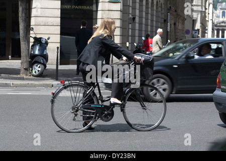 Una donna di Parigi è una bicicletta in strada indossando un nero business suit Foto Stock