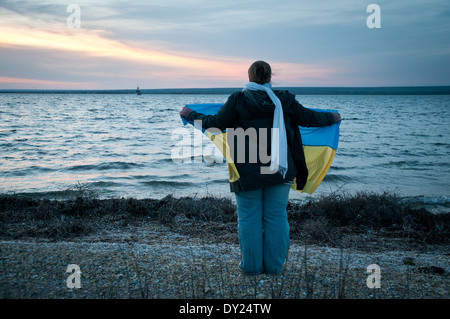 Pro-Ukrainian donna con una bandiera nazionale sorge su una riva del lago Donuzlav a sostegno di marines da U311 Cherkasy minesweeper Foto Stock