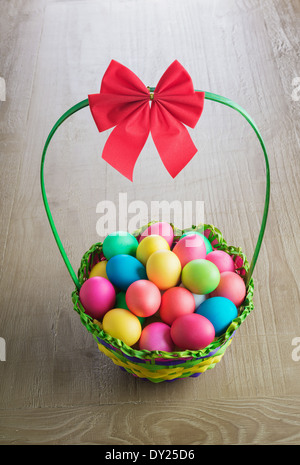 Multicolore di uova di Pasqua nel cestello wattled su vintage tavolo in legno Foto Stock