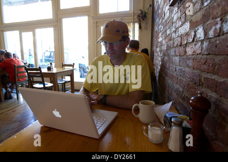 Uomo in occupato cafè usa il computer portatile mentre si beve il caffè Foto Stock