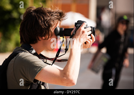 L'uomo le riprese con una Canon fotocamera reflex digitale, con la sua testa vicino all'occhio loupe Foto Stock