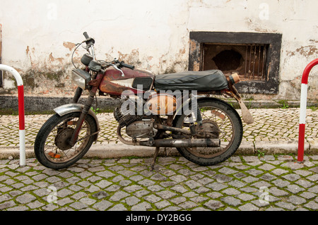 Vecchio arrugginito moto parcheggiata su strada Foto Stock