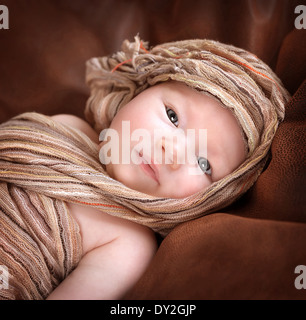 Closeup ritratto di carino neonato ragazza sdraiato sul letto e coperte con elegante scialle beige, baby fashion concept Foto Stock