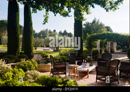 Sedie di vimini sulla terrazza in giardino provenzale con cipressi e oliveti Foto Stock