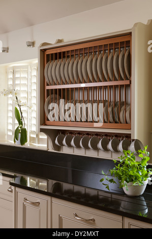 Piastra in legno stendino al di sopra di un granito nero del piano di lavoro con la pianta di basilico Foto Stock