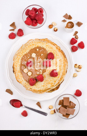 Pila di frittelle servite con cioccolato fuso e lamponi freschi Foto Stock