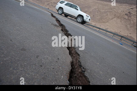 Alto Hospicio, Cile. 4 apr, 2014. Un veicolo transita accanto al marciapiede rotto in una strada, nella regione di Alto Hospicio, provincia di Iquique, il 4 aprile 2014. Il sistema di allarme precoce centro dell'emergenza nazionale ufficio (Onemi, per il suo acronimo in spagnolo) ha detto che ci sono stati circa centinaia di scosse di assestamento registrate attraverso giovedì nel nord del Cile, che ha colpito le regioni di Arica, Parinacota, e Tarapaca. Credito: Jorge Villegas/Xinhua/Alamy Live News Foto Stock