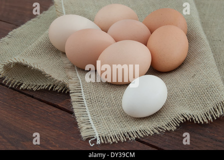 Otto uova di gallina sulla tela marrone recentemente rimosso dal nido Foto Stock