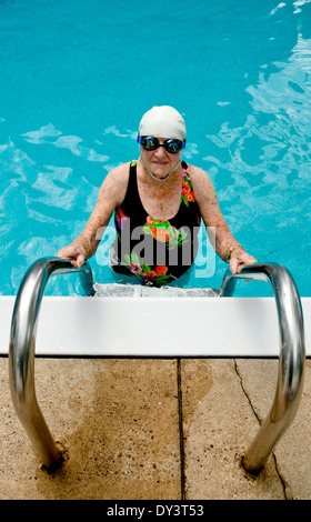 Un senior citizen donna in un costume da bagno, nuotare cappello e occhiali gode di uno stile di vita sano e rimane giovane a nuoto. Foto Stock