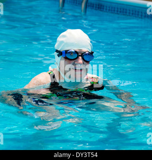Un senior citizen donna in un costume da bagno, nuotare cappello e occhiali gode di uno stile di vita sano e rimane giovane a nuoto. Foto Stock