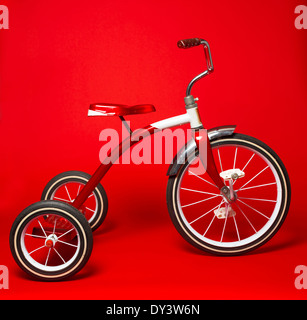 Un vintage red triciclo su un brillante sfondo rosso Foto Stock