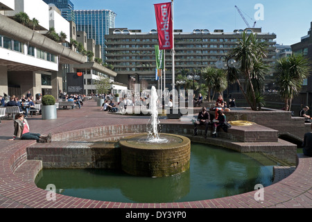 Vista della gente seduta dalla fontana al centro Barbican esterno ristorante Plaza Londra Inghilterra KATHY DEWITT Foto Stock