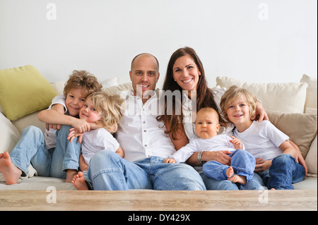 Quattro fratelli e i loro genitori seduto su un divano Foto Stock