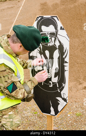 Un soldato dal Royal Irish Regiment ripara un target utilizzando la colla e la carta dopo la ripresa Foto Stock