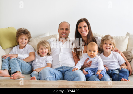 Quattro fratelli e i loro genitori seduto su un divano Foto Stock