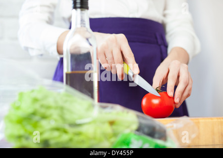 Lo chef femmina il taglio di un pomodoro per insalata Foto Stock