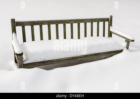 Snowy panca in legno coperto in un accumulo di neve in inverno Foto Stock