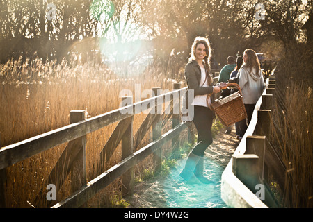 Giovani amici adulti che trasportano un cestino picnic sulla passerella Foto Stock