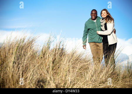 Coppia giovane passeggiando nelle dune di sabbia, Bournemouth Dorset, Regno Unito Foto Stock